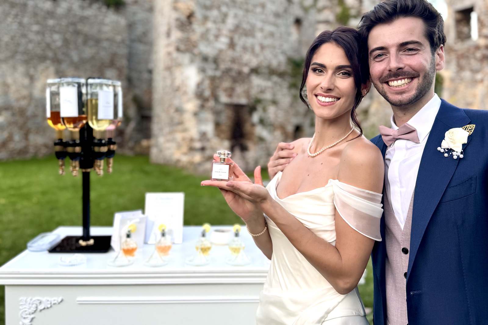 Mariés devant le bar à parfum L’Atelier MB Events au château, leur flacon sur mesure à la main