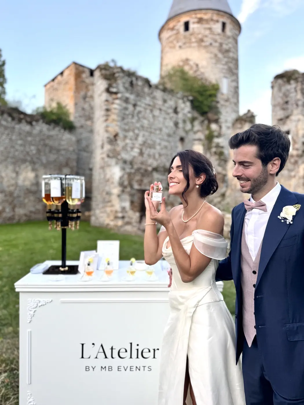 Mariés devant le bar à parfum L’Atelier MB Events, flacon souvenir en main